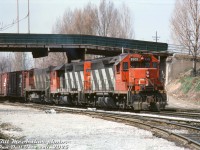 CN train #432 rolls eastbound through industrial Hamilton on the Grimsby Sub, lead by two of CN's small group of standard cab GP40's, 9302 and 9308, and M420 2552 trailing. The train is passing under the Mary Street overpass (alternate angle <a href=http://www.railpictures.ca/?attachment_id=45422><b>here</b></a>), with the CN Hagersville Sub branching off the Grimsby Sub in the foreground.
<br><br>
<i>Bill McArthur photo, Dan Dell'Unto collection slide.</i>