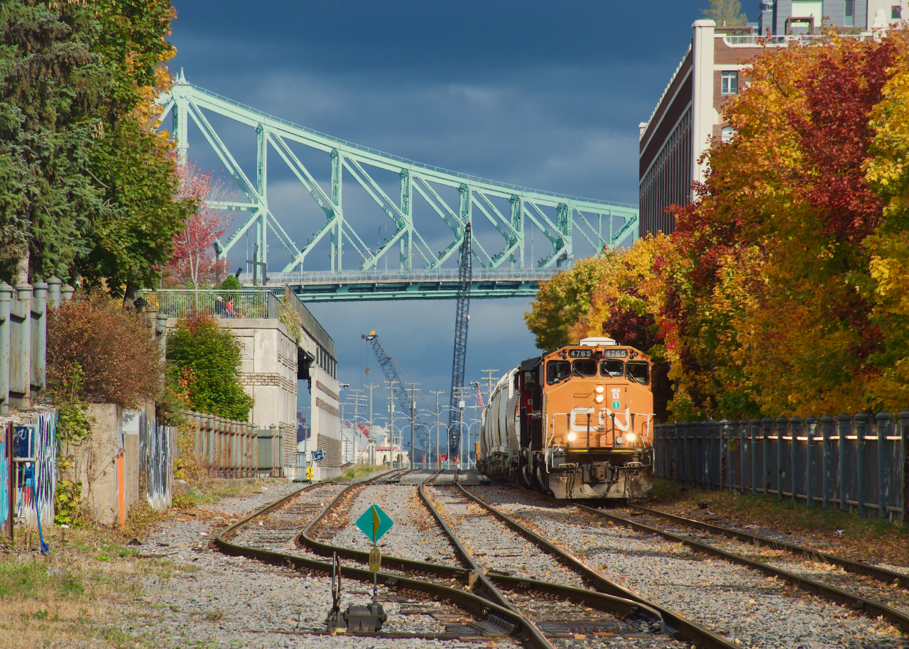 CN 500 is leaving the Port of Montreal under storm clouds as it passes some fall colours with CN 4765 leading.