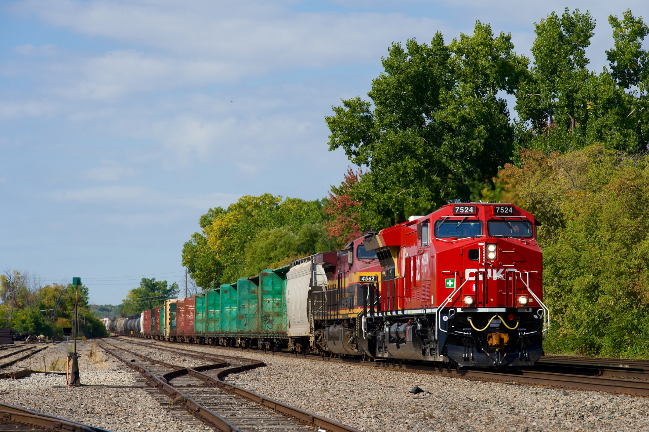 Fresh CP 7524 leads CPKC 2132 through Dorion, with KCMS 4652 trailing and KCS 4027 mid-train. At left is a small yard where commuter trains layed over for decades until a larger facility was built nearby a couple of decades back.