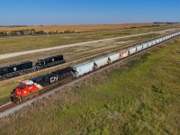 Harvest season is upon us.  A pair of Parish and Heimbecker units creep along the elevator track at Oban, slowly loading grain for export on the west coast. On the mainline, S 77581 13 races by with a 203 car frac sand train, bound for the oil fields of Western Canada, where “harvest season” runs year round. 
