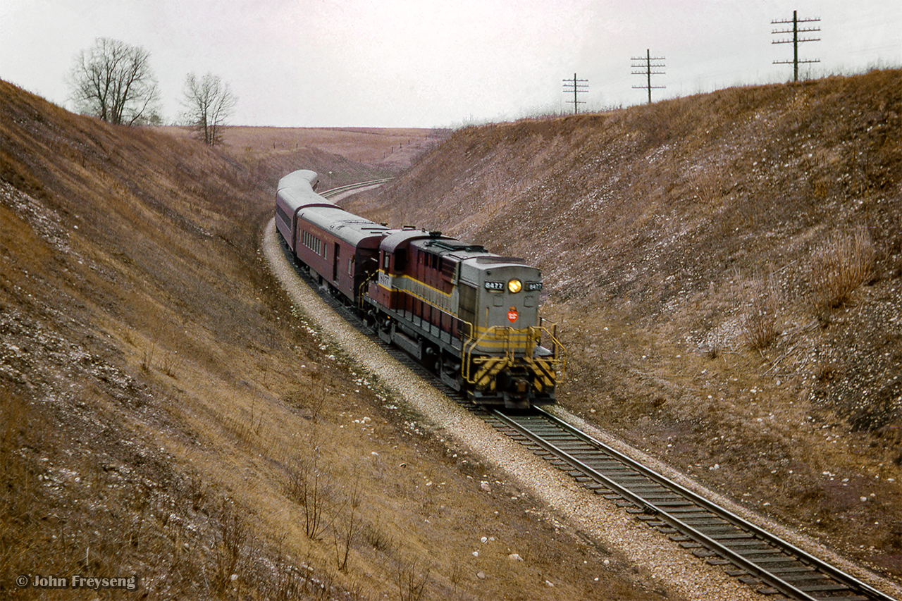 Windsor - Toronto train 38 descends the grade through Barrie's Cut between Galt and Orr's Lake.  Soon after, an eastbound freight led by a leased Lake Superior & Ishpeming RSD12 will follow eastbound.

Scan and editing by Jacob Patterson.