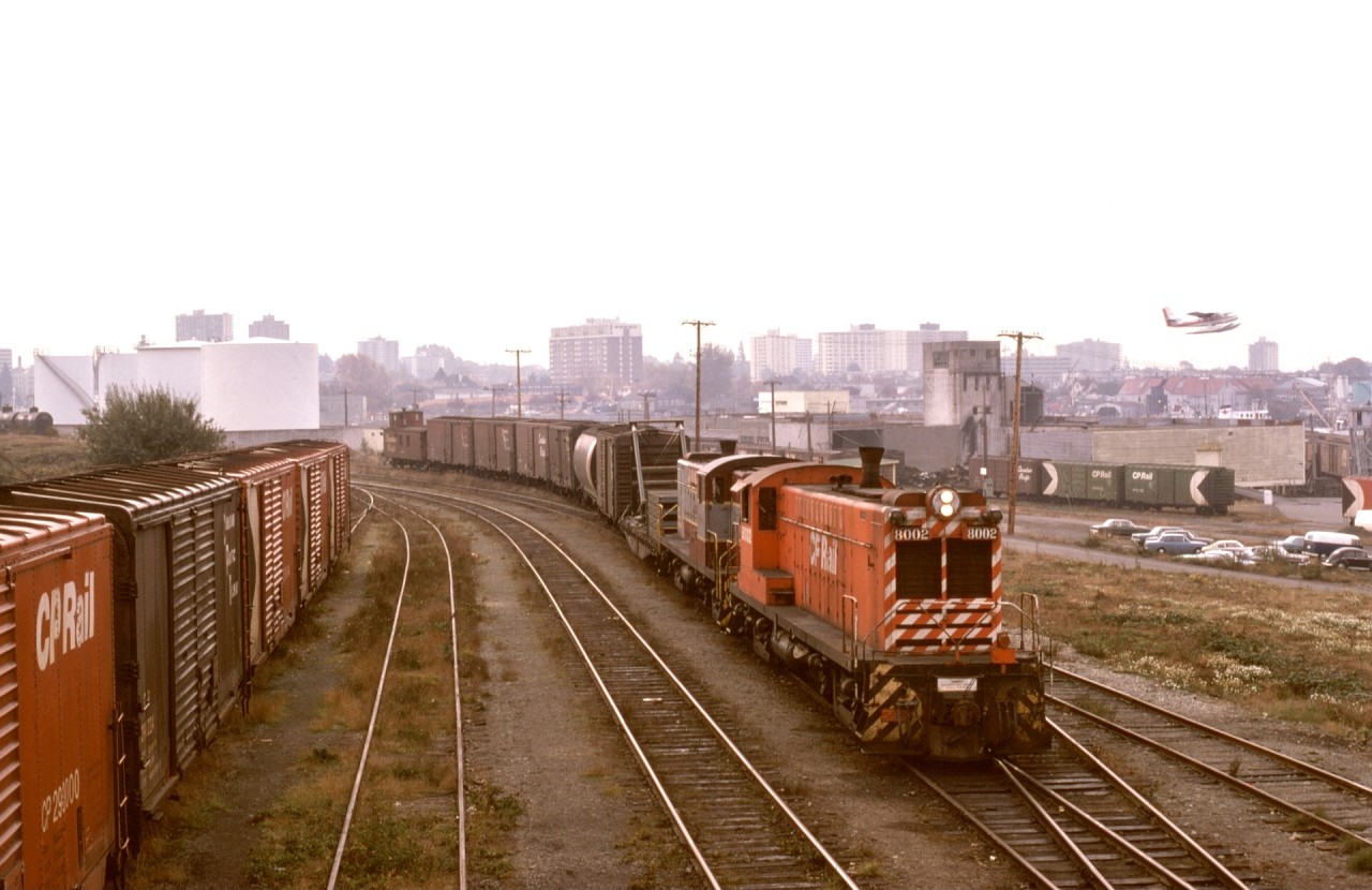 At Victoria on Thursday 1974-10-24, freight train No. 51 was all together and about to depart for Stockett and onward to Wellcox in Nanaimo with Baldwins CP 8002 and 8000 for power.  Below on the right were cars for or from US interchange via Island Tug and Barge.

(p)On the extreme right of the photo, the railbarge facility with a loaded barge at the slip can be seen.  My understanding is interchange traffic went to Port Townsend or Seattle, particularly newsprint loads from Port Alberni for San Francisco.