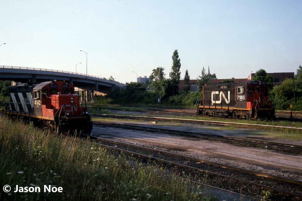 CN GP9RM 4142 and SW1200RSm 7105 are catching the first morning light of the day at the CN yard in Niagara Falls, Ontario. In later years, 7105 became CANAC Leasing (CANX) 7105 and was sent to the US to work at a Cargill facility in Bridgeport, Iowa. CN 4142 was retired in August 2001.