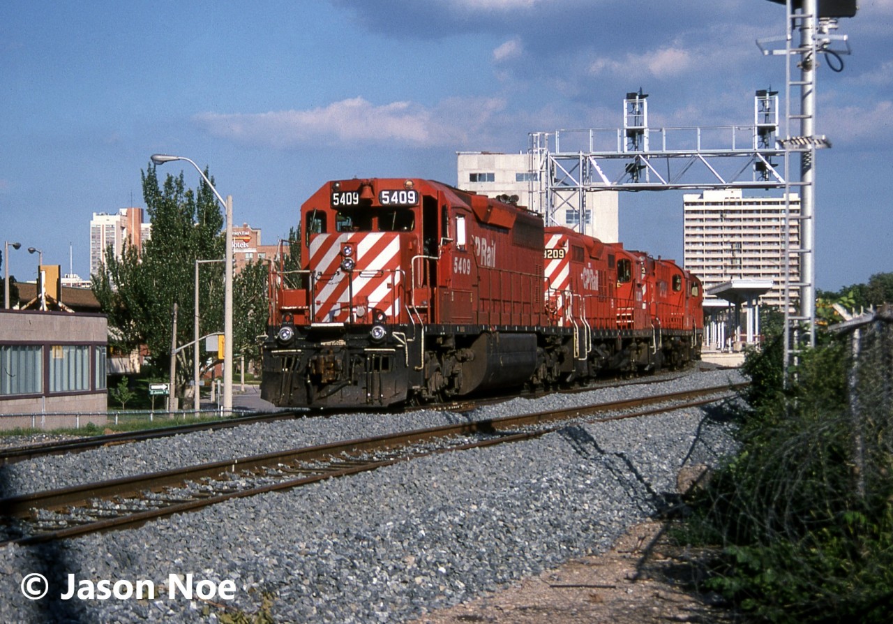 CP train 521 is viewed passing the site of the future downtown Hamilton, Ontario GO Transit Centre at the former Toronto Hamilton & Buffalo Railway (TH&B) station. At the time, construction was ongoing for the modern facility to open the following year on April 30, 1996. Also, the train is passing a new signal bridge that was already installed, however not functioning yet. 521 operated daily from Binghamton New York to Toronto and was powered by SD40 5409, GP9u 8209, RS18u 1803 and RS18u 1848.