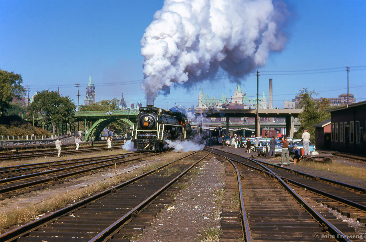 During a stop over in Ottawa after the overnight Toronto - Ottawa leg of the massive 692.2 mile trip behind CNR 6167, the morning CPR movements are out of the way, and 6167 can prepare to take the 17 car train across northern Ontario.  Switching movements commence beneath the Laurier Avenue Bridge with the Parliament Buildings towering over the scene at left, and the Chateau Laurier at centre.

Scan and editing by Jacob Patterson.