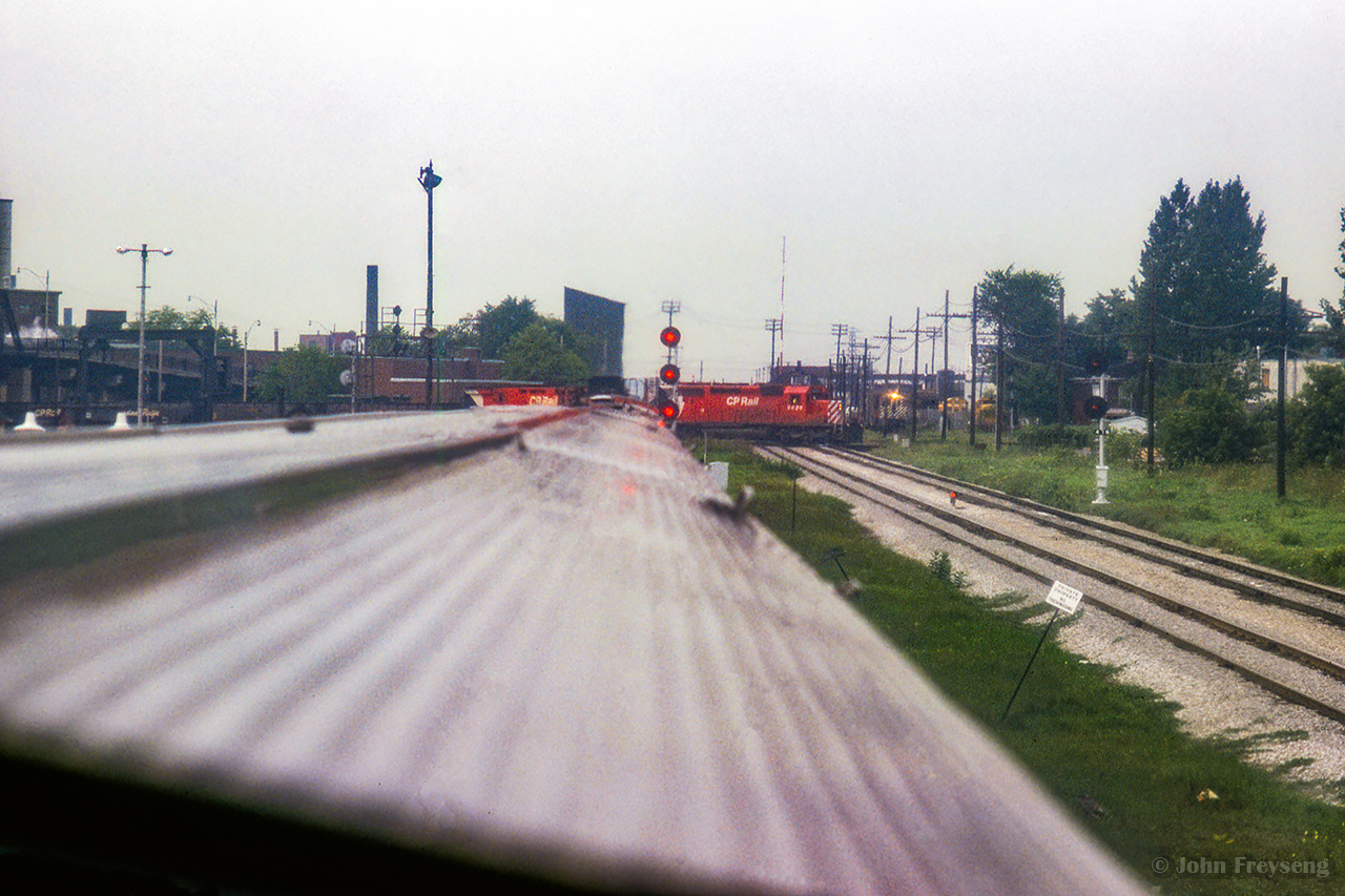 Lots of activity at West Toronto as the Canadian takes on passengers and waits to cross onto the Mactier Sub.  An eastbound freight behind an SD40-2 and a big MLW pound across the diamonds, while an MLW switcher can be seen waiting to clear the Mactier Sub.  Also note two yellow switchers in Andrew Merrilees yard.

Scan and editing by Jacob Patterson.