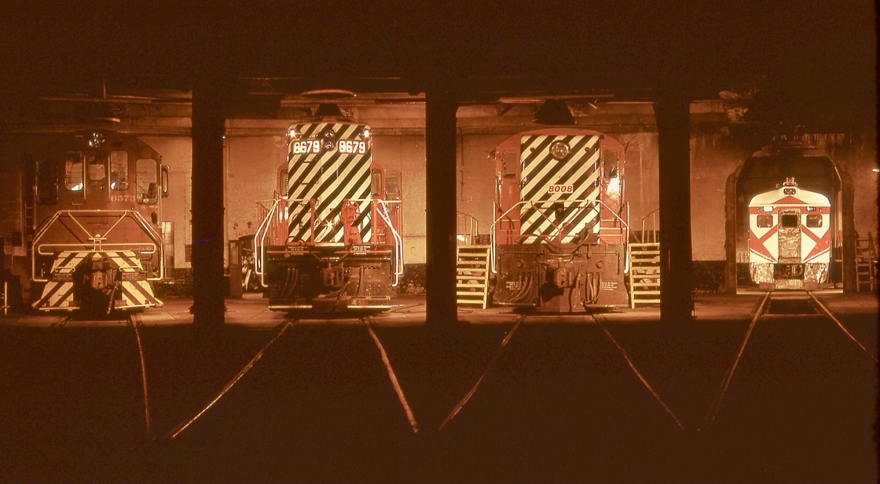 Sunday graveyard shift on 1972-05-28 at the E&N Victoria roundhouse gave me a perfect opportunity to start the second roll of Kodachrome in my week-old Pentax Spotmatic camera, with a collection of locomotives spanning four manufacturers.  From the left in stall 4, MLW S-3 CP 6573, GMD GP9 CP 8679, Baldwin DRS4-4-1000 CP 8008, and in the backshop beyond stall 1, Budd/CC&F RDC2 CP 9199.

Through the distant open door to the left of 8679, the shop steam generator that was in my post last week can be seen.

This was an early colour night shot for me, minimal knowledge of reciprocity effect, and completely ignorant of possible lens filter effects.  Learning came fast!

A very Merry Christmas and Happy Holidays to all.