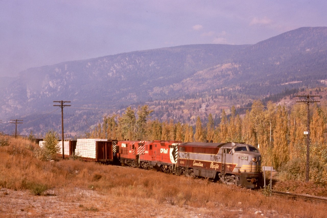Fortunate timing in my life with a driver’s licence and vehicle in 1973 allowed me to see the last full year of Fairbanks-Morse locomotive activity on CP, centred on Nelson.  On Friday 1974-10-11, a train returning from Midway to Nelson was a prime target, with a mixed consist of CP 4104 leading GM 8509 and FM 8555 and GM 8526, shown here leaving Kraft in forest fire haze and passing the mileboard to Robson West and milepost 28 to Nelson.