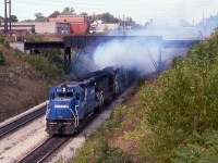  In a cloud of blue diesel exhaust, Conrail YDLN-2 appears to explode from the Detroit River Tunnel into Windsor, Ontario passing beneath the Essex Terminal Railway 'Black Bridge'.  The symbol YDLN means the job originated at Lincoln Yard (Y=Yard D=Detroit Div LN=Lincoln Yard)