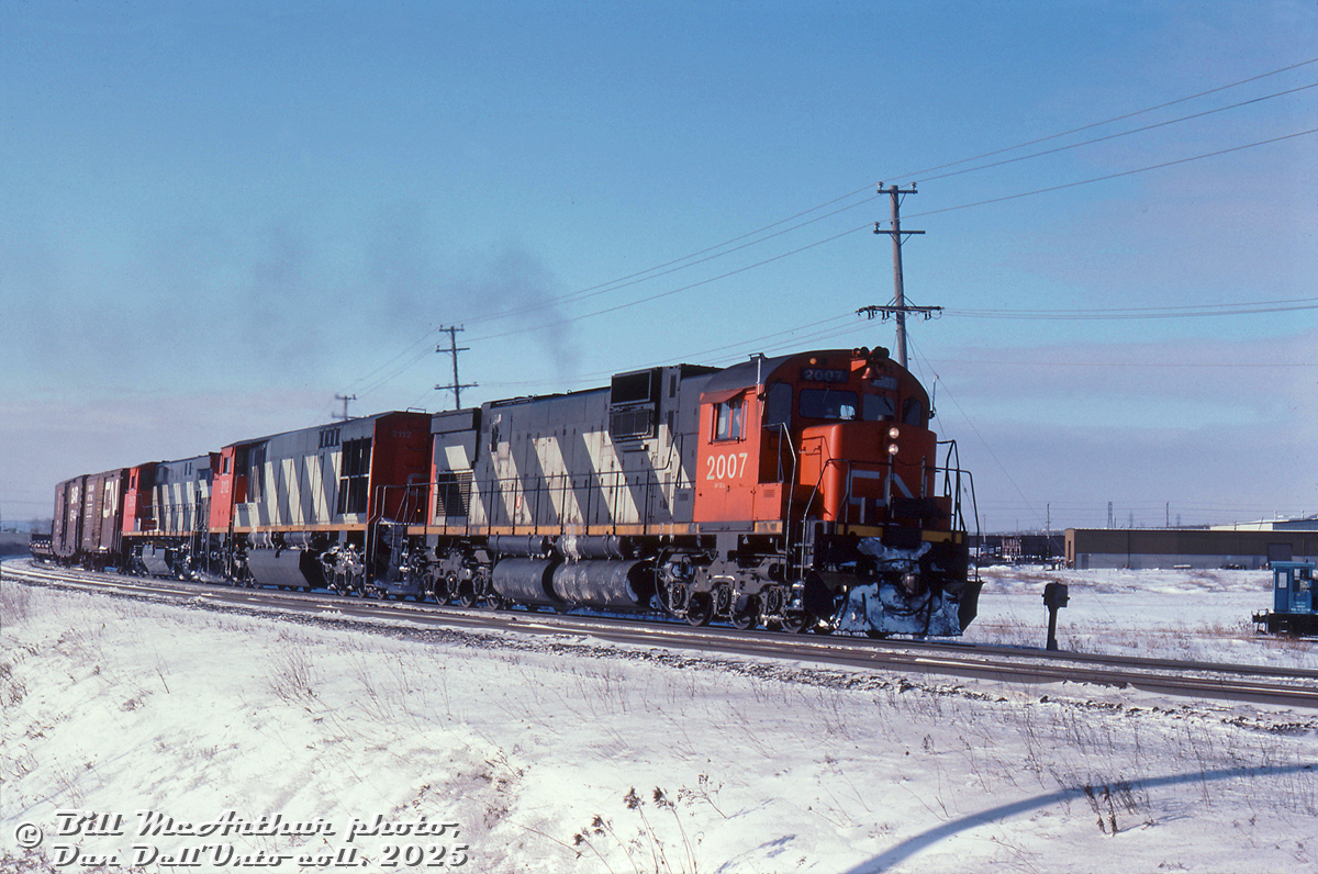 A cold, clear morning trackside yields an all-MLW lashup of CN C630M 2007, HR616 2112 and M420 2551 rolling an eastbound freight up the Halton Sub, curving north about to pass Walker's Line. The critter in the background is for the Canadian General Electric plant that was once here, that had its own siding.

Bill McArthur photo, Dan Dell'Unto collection slide.