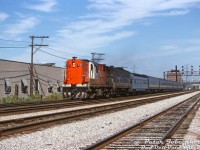 CN Tempo RS18 3153 leads VIA F9B 6633 westbound on the Oakville Sub on VIA train #83, heading through Mimico East leaving the QEW overpass, L.J. McGuinness distillery and Stelco Swansea plant in the distance. Today's consist of blue and yellow ex-CN passenger cars is led by one of the former Reading "Crusader" observation cars (300 or 302), that will likely take its turn on the tail end of the train on the trip back to Toronto.
<br><br>
<i>Peter Jobe photo, Dan Dell'Unto collection slide.</i>