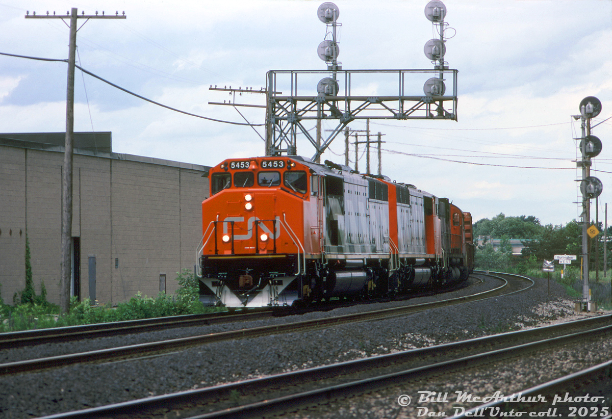 Nearly new (3 months old at the time) CN SD50F units 5453 and 5450 lead C630M 2036 on a westbound freight, coming off the Halton Sub at Burlington West (note the added "West" sign).

The new full-bodied Draper-Taper cowl units, CN's second SD50F order from GMD, were still being built with EMD's 645F engine despite EMD already introducing the 710G in the SD60 model three years earlier (and CN ordering 4 prototype SD50AF units equipped with the 710G two years earlier. Perhaps CN hadn't fully assessed them yet). It would be another two years before CN ordered their first 710G-engined SD60F units (5504+).

Bill McArthur photo, Dan Dell'Unto collection slide.