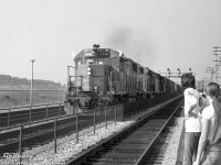 With white extra flags waving in the wind and marker lights selected to "white", an eastbound extra freight lead by CN GP38-2 5518, a GP38-2W, and another GP38-2 sails through Eglinton GO station, catching the eye of waiting passengers on the platform awaiting the arrival of the next GO train inbound to downtown Toronto.<br><br><i>Bill Grandin photo, Dan Dell'Unto collection negative.</i>