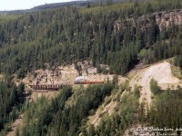 An early Canadian Pacific Railway 4-4-0 steams through the rough Rocky Mountain landscape out west, hauling two wooden passenger cars through mountainside wilderness cut through by steel rails laid over wooden trestles and through rock cuts, along the new transcontinental railway line spanning Canada from coast to coast.<br><br>That was the intent the CBC's film directors wanted to portray - a rocky, rough, sometimes treacherous, and vastly untamed mountain wilderness that the transcontinental railway line had to be built through in western Canada. And for that film crews (guided by technical consultants like Omer Lavallee) turned to the Carmi Sub in Myra Canyon (east of Penticton BC) for shooting various scenes for their 1974 film adaptation of Pierre Berton's "The National Dream" book on building the Canadian Pacific Railway. <br><br>For the live steam scenes, <a href=http://www.railpictures.ca/?attachment_id=47318><b>CPR 4-4-0 136</b></a> (double-billed as both 136 and 148 for different scenes) was borrowed from the Ontario Rail Association and backdated to a late 1800's appearance, and some vintage passenger and freight equipment was rounded up by CP from their work car fleet across the system and turned into close-to-period-correct freight and passenger cars for use during the different filming scenes, including the track laying and general scenic scenes such as this.<br><br>Operations on this section of the Carmi Sub (Beverdell to Pentiction) had recently been discontinued by CP, but the line was reopened one last time for filming all the mountain scenes. Upon completion of filming, a diesel locomotive and caboose were dispatched for one final movement in order to retrieve the film's railway equipment and forward it to other parts of the system. A small section of the line to the east saw service for a short period longer, but The National Dream filming were the last train movements on the western part of the Carmi Sub. The line has since been converted into a popular walking/cycling trail.<br><br><i>Eric W. Johnson photo, Dan Dell'Unto collection slide.</i><br><br>More from The National Dream:<br>Tracklaying: <a href=http://www.railpictures.ca/?attachment_id=55064><b>http://www.railpictures.ca/?attachment_id=55064</b></a><br>Filming: <a href=http://www.railpictures.ca/?attachment_id=55074><b>http://www.railpictures.ca/?attachment_id=55074</b></a><br>Prairie consist: <a href=http://www.railpictures.ca/?attachment_id=56449><b>http://www.railpictures.ca/?attachment_id=56449</b></a>