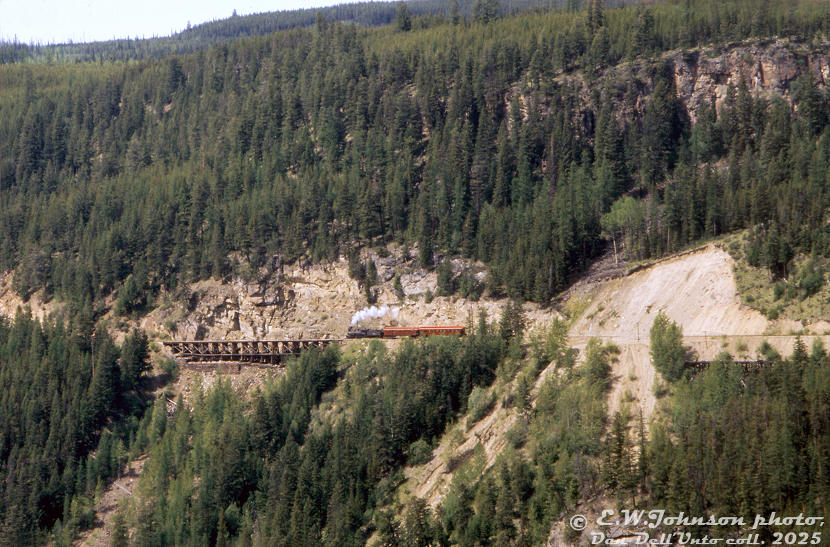 An early Canadian Pacific Railway 4-4-0 steams through the rough Rocky Mountain landscape out west, hauling two wooden passenger cars through mountainside wilderness cut through by steel rails laid over wooden trestles and through rock cuts, along the new transcontinental railway line spanning Canada from coast to coast.

That was the intent the CBC's film directors wanted to portray - a rocky, rough, sometimes treacherous, and vastly untamed mountain wilderness that the transcontinental railway line had to be built through in western Canada. And for that film crews (guided by technical consultants like Omer Lavallee) turned to the Carmi Sub in Myra Canyon (east of Penticton BC) for shooting various scenes for their 1974 film adaptation of Pierre Berton's "The National Dream" book on building the Canadian Pacific Railway. 

CPR 4-4-0 136 (double-billed as both 136 and 148 for different scenes) was borrowed from the Ontario Rail Association and backdated to a late 1800's appearance, and some vintage passenger and freight equipment was rounded up by CP from their work car fleet across the system and turned into close-to-period-correct cars for use during the different filming scenes.

Operations on this section of the Carmi Sub (Beverdell to Pentiction) had recently been discontinued by CP, but the line was reopened one last time for filming all the mountain scenes. Upon completion of filming, a diesel locomotive and caboose were dispatched for one final movement in order to retrieve the film's railway equipment and forward it to other parts of the system. A small section of the line to the east saw service for a short period longer, but The National Dream filming were the last train movements on the western part of the Carmi Sub. The line has since been converted into a popular walking/cycling trail.

Eric W. Johnson photo, Dan Dell'Unto collection slide.

More from The National Dream:
Tracklaying: http://www.railpictures.ca/?attachment_id=55064
Filming: http://www.railpictures.ca/?attachment_id=55074
Prairie consist: http://www.railpictures.ca/?attachment_id=56449