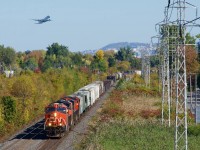 CN 3153, CN 2963 & CN 3190 is up front on CN 369 as a plane takes off above it.