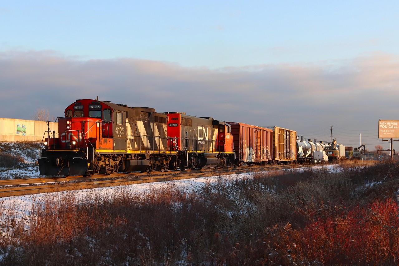 At 70 years old, CN 4125 leads L551 eastbound on the south track passing a work crew and machinery preparing ductwork at Appleby Line overpass for fibre-optic cable installation to the Milton Logistics Hub.