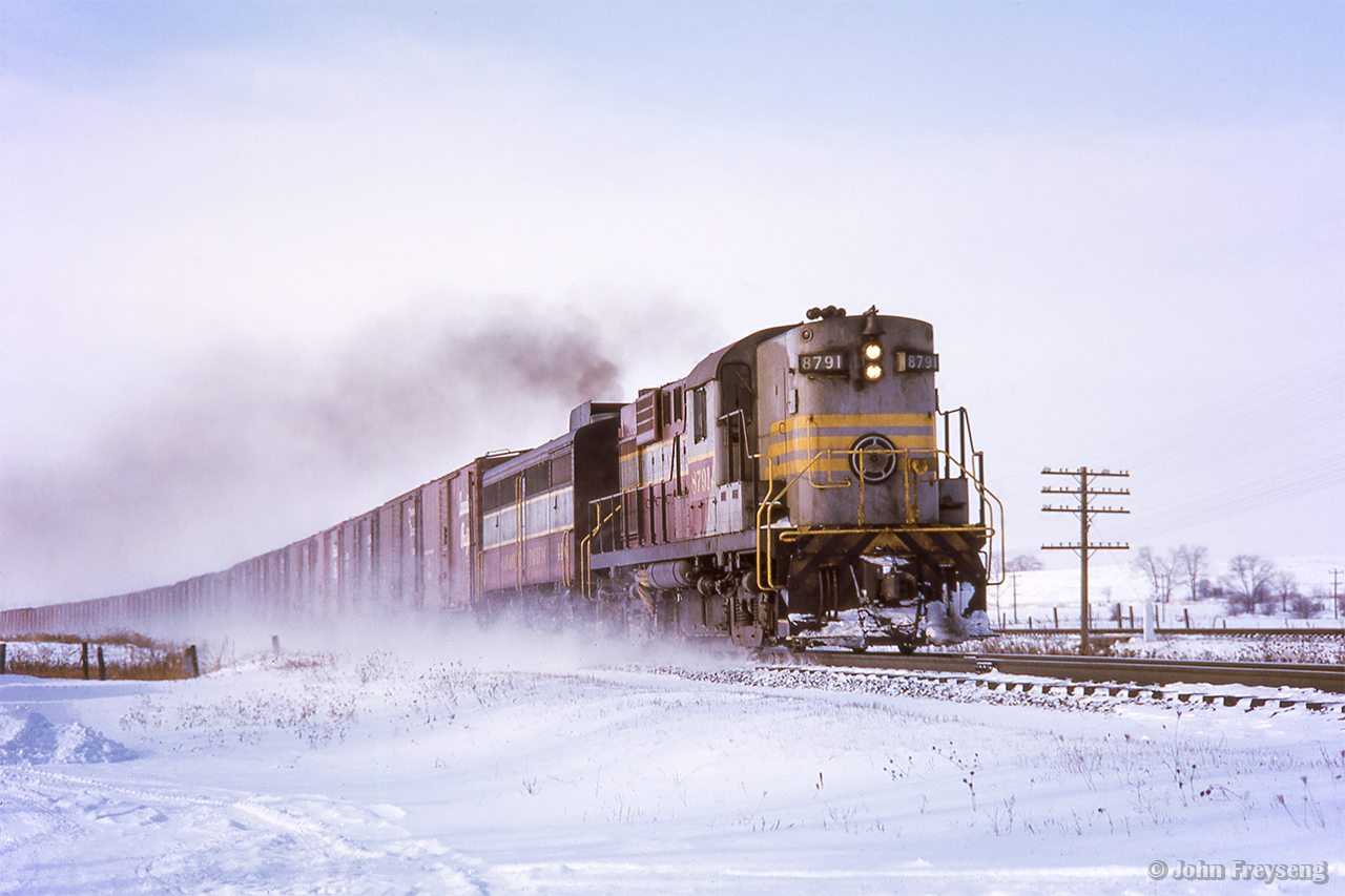 An eastbound CPR freight kicks up the snow approaching the Highway 2 crossing between Cobourg and Spicer.

Scan and editing by Jacob Patterson.