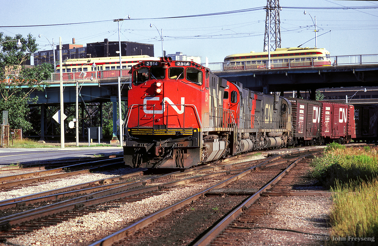 CN Extra 2514 makes its way down the Bala Sub, passing under Queen Street, where TTC streetcars are seen meeting.

Scan and editing by Jacob Patterson.