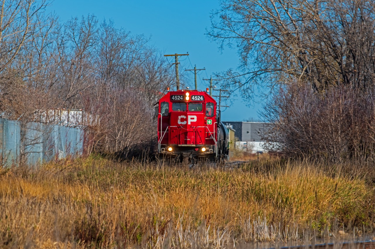 Slowly rolling their way through the tall grass along a little spur line off the CPKC Emerson sub, after switching taker cars at Brenntag.