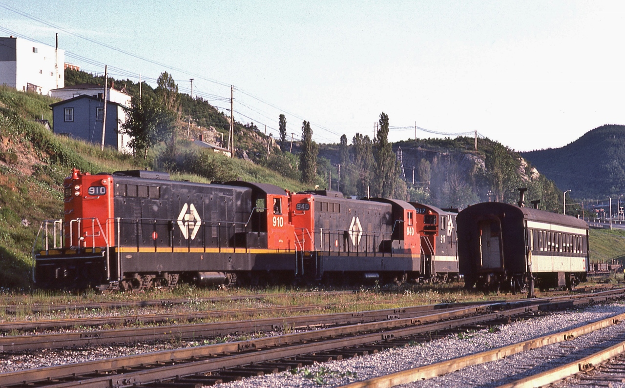 …....“ the Narrow Gauge gets into your blood – it will not 'out' ”....

 
Terra Transport's  daily train #204's power shuffles cars,

 
and the final move is to attach the CN ( TT - open window) Coach onto the consist to comply with the Transport Commission's order to provide the remote 137 mile route with daily passenger service* from Corner Brook (departing 18:45) to Bishop's Falls (arriving 23:35). 

 
At Corner Brook, August 2, 1982 Kodachrome by S.Danko

 
The Power:

 
four GMD 1956 to 1960 built NF210's: TT#910 ; TT#940 ; TT#917 ; TT#919 (CN noodle) 

 
plus TT#918 in tow (CN zebra livery) - ground out relay issue 

 
Note the fresh ballast on the main track (foreground).

 
Today, I understand that the rail right-of-way is now a vehicle highway.

 
   *  VIA Rail System Timetable dated November 15, 1981, Table #2. Bishop's Falls – Corner Brook  daily Mixed Trains #203 and #204: reference mark #1 No Checked Baggage. “Mixed Train Services are operated by Terra Transport Ltd.”

 
More
 

      204's power 
 

      Wreckhouse, Nfld 

 
sdfourty