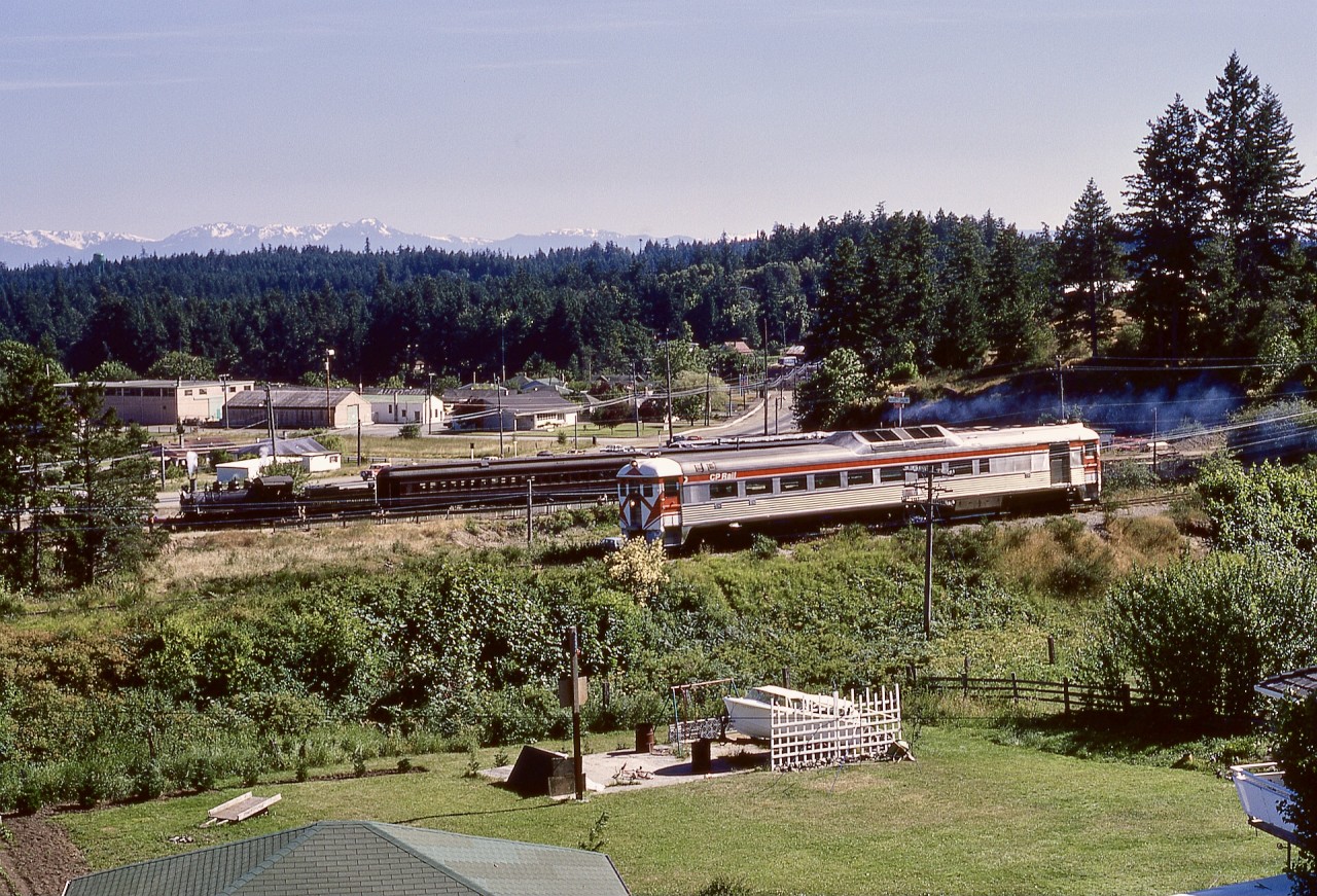 During the short period of Victoria Pacific tourist railway operation on a short section of CN’s Cowichan subdivision west of Victoria, one of my photo goals was to document CP’s E&N southward Courtenay-Victoria passenger train No. 2 with Victoria Pacific equipment in the background, ideally with sunlight on the near side.  Near the summer solstice, on Saturday 1972-07-01, that worked out, with CP 9199 on No. 2 and former Comox Logging & Railway 2-8-2 Baldwin number 16 getting ready to depart Millstream Junction on the last run of the day, as seen from up on the TransCanada Highway.