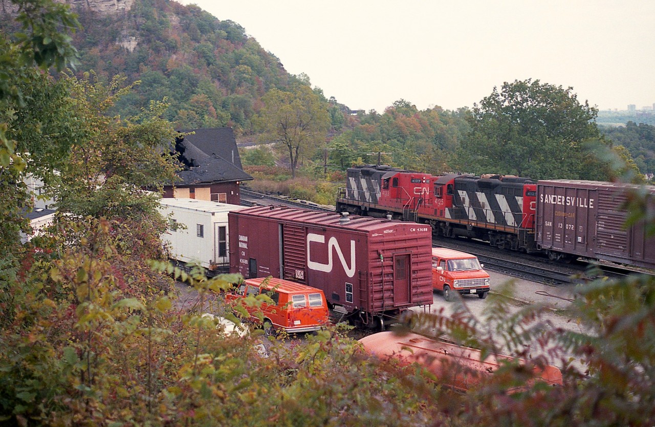 There was quite the gathering of various MoW equipment and vehicles at the Dundas station when I showed up on this rather decent early fall day. I had just returned home from Oneonta (NY) and the D&H when I heard a fire has caused quite a mess at the old station, so headed up to check it out. Not sure of the cause, but it was initially said to be arson; the waiting room went up and burned thru the roof. This was on September 27th, and by Oct 2nd when I arrived the place had been tightly boarded up.
Not sure what all the activity this day was about. CN's 4133 and 4125, which I 'think' was the Hamilton to Brantford and return local, rolls slowly eastward past the action, completing an interesting scene.
An attempt to save the station and have it moved was on the table, but various misfortunes resulted in the idea tossed and the station demolished.