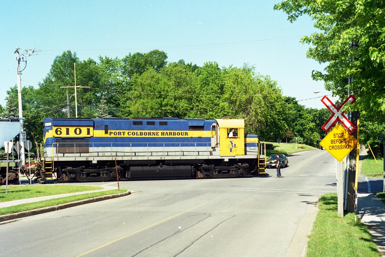 ALCO C-425 #6101, lettered for the fledgling Port Colborne Harbour Railway, is seen heading back to WH Yard after working Goderich Elevator down on the harbour.  This is the first road intersection on the return; crossing Sugarloaf at Elm St on a nice sunny and very warm afternoon. The old locomotive was returned to the New York and Lake Erie railroad in 2001 and is now on the roster of the Delaware-Lackawanna in Pennsylvania.
The PCHR at this time was in its' infancy. The official Grand Opening ceremonies were still a week away.