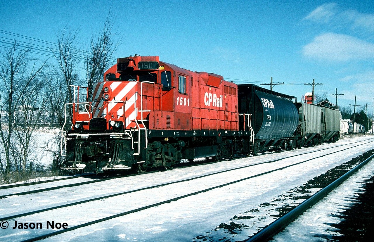 The typical weekday for the CP Guelph local’s crew was to switch the small yard and the nearby lumber yard at Guelph Jct. during the morning. This occurred after all the weekly morning GO Transit sets departed eastbound for Toronto. After its work at Guelph Jct. was completed the job would depart westbound on the Galt Subdivision to Puslinch to service the transload that was situated beside the siding and mainline. At the time, this track (G90), was quite active with several different companies depending on it for rail service. They included; GE Phillips Forwarding, Central Ontario Transfer, Orica Canada and the Upper Canada Stone Company. Following its work here, the crew would return to Guelph Jct. where they would complete any additional switching prior to departing for Guelph if required with usually a small train.

Here during a frigid sunny winter day, CP GP7u 1501 is pictured working the transload track which was quite full at the time.