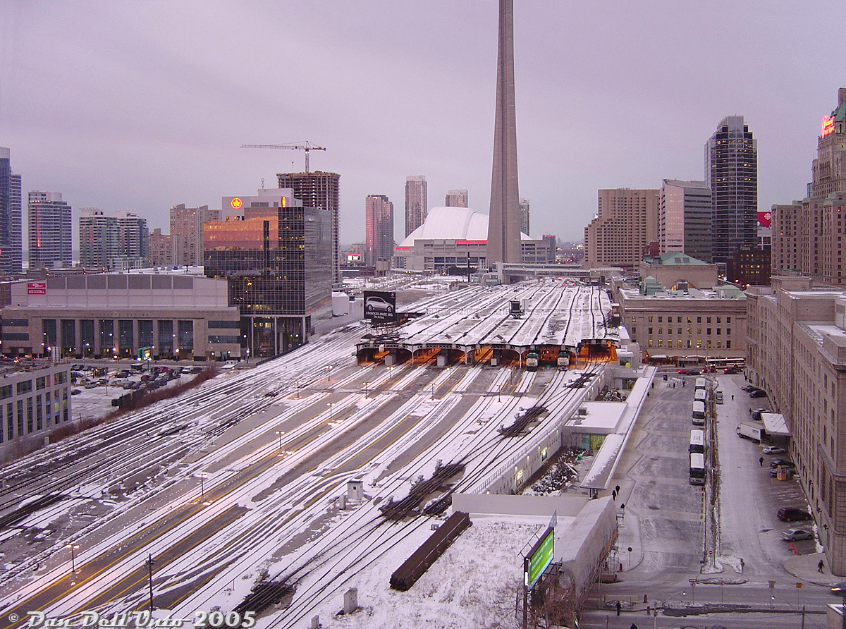 Early morning weekday at Toronto Union Station. It's 7:43am and a dull pink hue from the budding sunrise casts itself over a cold winter scene downtown. Switch heaters hum quietly and the odd clicking of switch points being lined by the nearby Scott Street tower TMD can be heard against the general faint downtown noise.Three GO Transit F59PH's can be seen under the drafty train shed: 535 on Track 4 about to depart with eastbound #406 to Pickering, an unknown unit on Track 3 (likely on #477 departing for Burlington soon), and another unknown unit on Track 1 (possibly #832 recently arrived from Richmond Hill). Soon the endless clickity clack of additional F59's and bilevels passing their way through multiple slip switches on the ladder tracks right outside the window would follow, as more morning trains arrived from the east and deadheading equipment moves departed for their next runs.Down at Union Station it's just starting to get busy, with sleepy commuters flooding the GO concourse off recently arrived Oshawa, Hamilton, Richmond Hill, Oakville and Milton inbound trains, some ordering breakfast at the McDonalds, grabbing a coffee from the Second Cup, a paper from one of the Gateway Newstand kiosks, or maybe a tasty snack from Mmmuffins or The Bagel Shop before hitting the PATH network or subway to work or school (it's a bit too early to hit up the Cinnabon or LCBO, unless you're a certain kind of person).Outside it's mostly quiet at the nearby Union Station bus terminal as stray GO buses lay over, including a 1600-series Prevost and some MCI D4500's (and it would remain mostly quiet until the rush hour trains stopped running and afternoon bus runs picked up). A TTC 6200-series GM/MCI "Classic" on the 6 Bay route waits at the bus stop on Bay Street outside the GO concourse entrance. Residents in the "few" (compared to today) surrounding condos are starting to get ready for work, and patrons staying at the Royal York Hotel are hitting their alarm clocks before dressing for important meetings downtown. Part of the John St. Roundhouse and coaling tower are barely visible and sit deserted, as the whole rail museum thing hasn't happened yet. Work continues on the Yonge Street viaduct rehabilitation project below, and traffic on Bay and Yonge is sparse with the Gardiner moving well for now. Skydome/Rogers Centre report: the dome is definitely closed today.The Canadian: on-time with VIA 6404 & 6432 leading. Amtrak Maple Leaf: on-time departure with P32AC-DM 702(!). CN local for switching the Toronto Portlands: eastbound with GP9RM's 7080 & 4100. Union Pearson Express: didn't exist yet. Number of MP40's seen: didn't exist yet. Northlander: still existed, but missed it (drat).Apparently it was to be very snowy in the afternoon and there was a very important computer science exam at the Ramsay Wright Zoological Laboratories to attend around the same time, thus the early trip into the city allowing plenty of review time (and avoiding any potential GO bus or train delays).