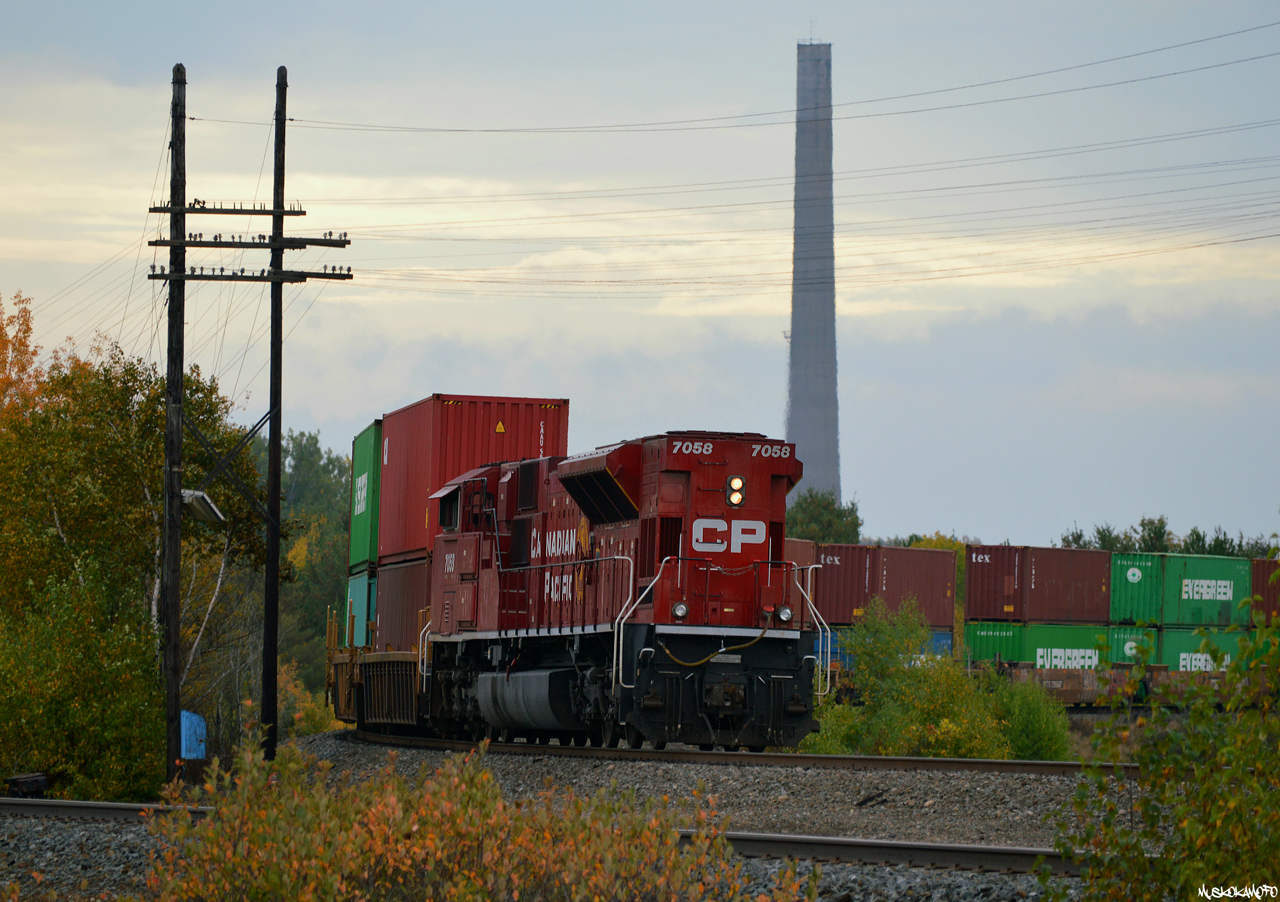 CP SD70ACU 7058, rebuilt from UP SD9043MAC 3551 (built 1/1997 as UP 8080), takes up the rear of CP 112 around the bend at the very top of the Parry Sound sub in Romford. While their sister "Super Stacks" in Sudbury are slowly being dismantled, one of the 2 "Twin stacks" built by Inco in 1954 and 1958 stands tall in the background. 

Idled in April of 1972 due to stricter environmental laws, the Coniston plant was kept as a "standby smelter" (although it was never used again), until most of the site but the towers and some original buildings was demolished in 1976. They have stood as part of the "Coniston Industrial Park" and the town's identity ever since, briefly being studied for the feasibility of retrofitting the two dormant 120-metre tall smokestacks with wind powered generation systems in 2007, ultimately resulting in a windmill farm being built further South closer to the French River.