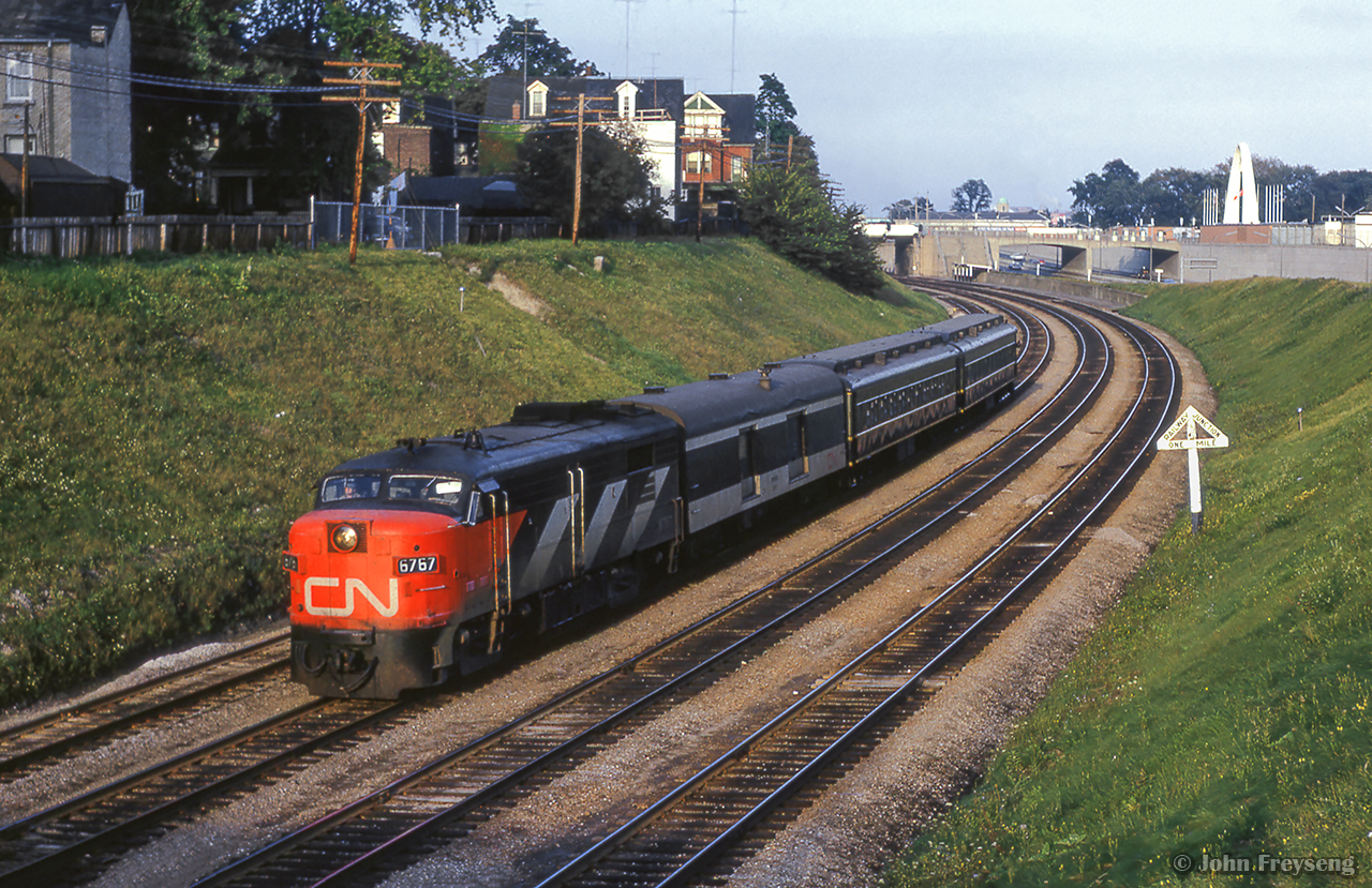 Toronto - Hamilton commuter 923 rounds the curve near Exhibition Station, about to pass under Dunn Avenue.  Note the "Railway Junction One Mile" sign in place for the CPR Wharf Lead just west of Strachan Avenue.

Scan and editing by Jacob Patterson.