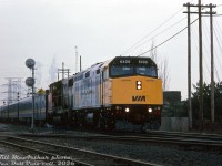 Brand new VIA F40PH-2D 6406 and seasoned CN GP40-2LW 9420 handle a decently-sized train #72 eastbound at Burlington Station, crossing over Brant St. underpass to the east. The fresh-looking 6406 was barely a month old, newly minted at the GMD London plant as one of the first of VIA's new modern F40 passenger units.
<br><br>
CN 9420 was an interm solution before the arrival of the new VIA power: one of 30 GP40-2LW's CN had modified in late 1984 for passenger service as-needed on VIA, including the addition of steam generator blowdown controls for operation with a steam generator car. On top of that, units 9400-9449 had also been delivered new with higher-speed 76 mph gearing for fast freight/intermodal service, making them ideal for pitch-hitting in passenger service in the southern Ontario area.
<br><br>
6000 horsepower should be more than enough to get this passenger train over the road, and the exact same power came back the next day on a westbound with the 9420 leading! One has to wonder why the 9420 was needed, but perhaps the new 6406 was still being broken in, and a second unit was needed as protection power.
<br><br>
<i>Bill McArthur photo, Dan Dell'Unto collection slide.</i>