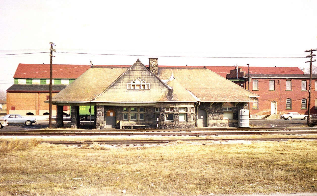 Such the impressive structure.  It soldiers on to this day as the Mettawas Station Mediterranean Restaurant. (No, I have not tried it) Once the station was declared expendable after the railway ceased operations thru here, it sat vacant. A determined effort by the locals saved it.
The station that once served Lake Erie, Essex and Detroit River Railway was built in 1889, solely of local fieldstone and timber, by Hiram Walker. Business was brisk since he also had a hotel and casino down by the lakefront.
Once upon a time this busy main line location had a yard, water tank, freight office and spur lines to various industries that located close by. They included grain facilities, fruit storage and especially tobacco businesses.  I believe that was a tobacco establishment you can see behind the station. I do know it is now the site of many new homes...... (note MoW car behind station)
The rail line is gone and the Chrysler Greenway trail corridor opened on the site in 1997.
