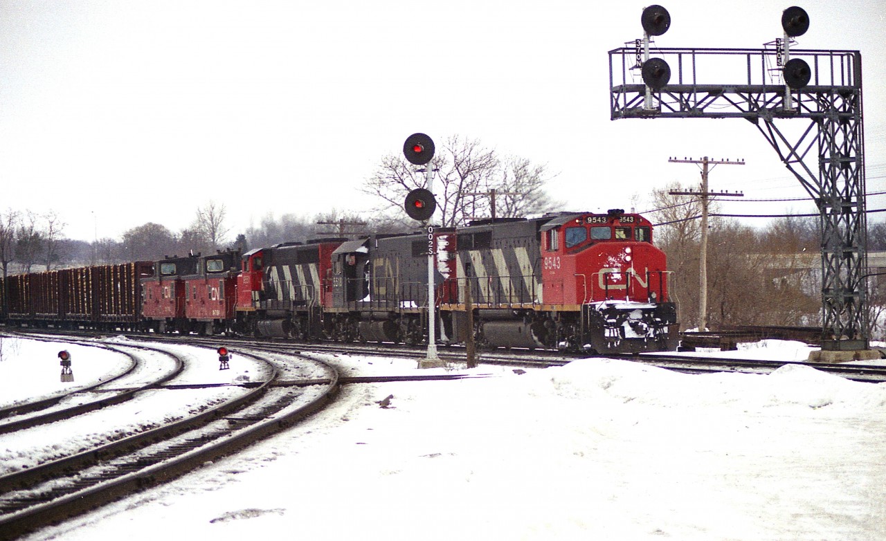 This image, on this day, as I enter this to RP, it is exactly 48 years ago. It is snowy and cold.......hey, its February; and the daily "Pulp train" is making its way thru to Niagara.
The power is CN 9543, 5518, 9551, with two vans behind; 79594 and 79760.  There were 46 cars on this train and van 79797 brought up the rear.
This train was so distinctive (more so in the summer when you could smell the fresh logs) that I would write in my notes "The Pulp Train" and neglect to record the actual train number. Me bad.