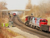 Copetown memories:
The original track was laid thru here back in the 1850s by the Grand Trunk. Problems developed in this stretch of track between mile 9.0 and 9.1 Dundas sub after a second track was put in. Apparently the underlying ground was of a sandy silt nature and ground water seeping in caused some instability in the track bed. Problems grew worse as trains became more frequent, longer and heavier. Water was at times pooling between the rails.  By 1995 a slow order restricted trains to 5 MPH over this stretch and a watchman was on duty 24 hours a day who kept an eye on the railbed as each train rolled over. CN shored up and realigned the track frequently. Beginning around 2013 and completed not long after, the railroad using new technology put a hopefully permanent end to the problem, and the slow order lifted and watchman removed.
In this photo, eastbound, coming at the photographer is #386 with CN 9489, CR 6479, CN 7106 and 4132. Heading west is #387 powered by CN 5626, GT 6413 and 6205.
Off to the left by his "shanty" stands the watchman. Note he has some conveniences, such as his lawn chair so he can sit out and catch some rays.  I wonder if he cut his own patch of lawn, too?
Not that many winters ago, maybe 2020, I walked the access laneway that led to the long gone shanty, and despite it was well below freezing, water was bubbling out of the hillside and running down thru the gravel.
The problem, in a minor way, still persists.