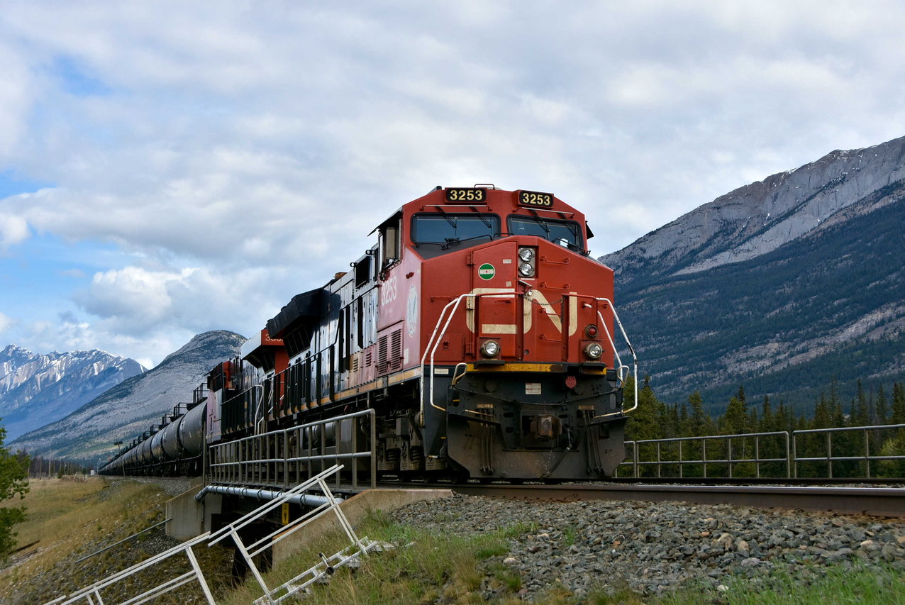 CN 3253 waits with an LPG train behind on a section of double track main. Mt Hawk is in the background. Note the classic signal bridge in the distance.