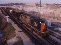 CN GP9 4511 and QNSL SD40 204 roll past the future site of the Aldershot GO station on a nice spring evening in 1969. As you can see, the lot used to be occupied by the large J Cooke Concrete Blocks business with a small CN yard (built in the 1960s) opposite.