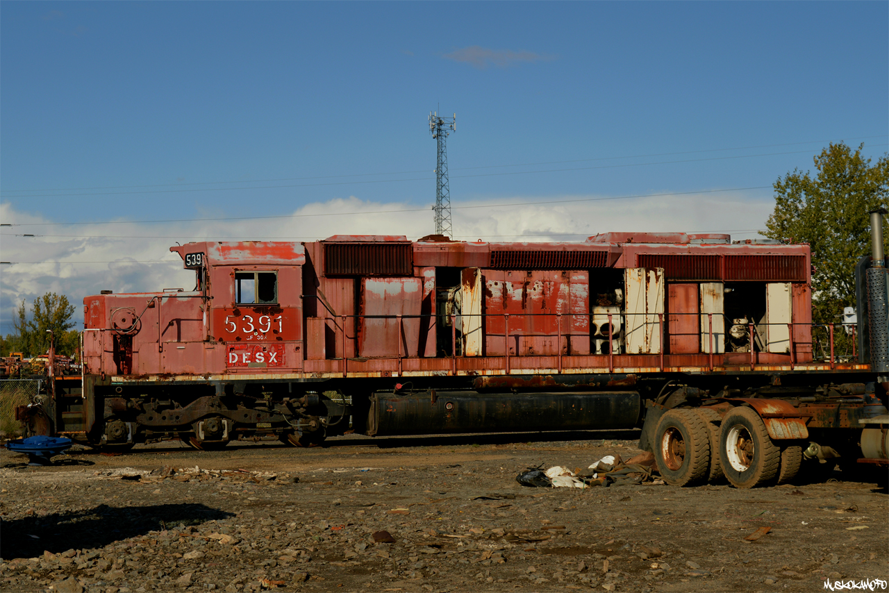 DESX 5391 sitting in the sun at DESX (now Mansour Rail)'s yard in the North East end of Sudbury showing all of her past lives, how many logos can you spot?! While I'm not sure on the exact date, shortly after this photo was taken 5391 was scrapped onsite after plans for it to become a test bed changed. During my final of several attempts at buying the numberboards, the manager (who was confident they'd need them again), noticed I had boots on and said "why don't you head in there and grab some pictures of it up close for once instead of over the fence!", deal! 

For more info on 5391, click  here