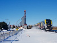VIA 24 passes a maximum 30 kmh road sign as it flies by at probably about quadruple that speed. At left is a mill at Saint-Polycarpe that CN 589 will lift cars from a dozen minutes later.