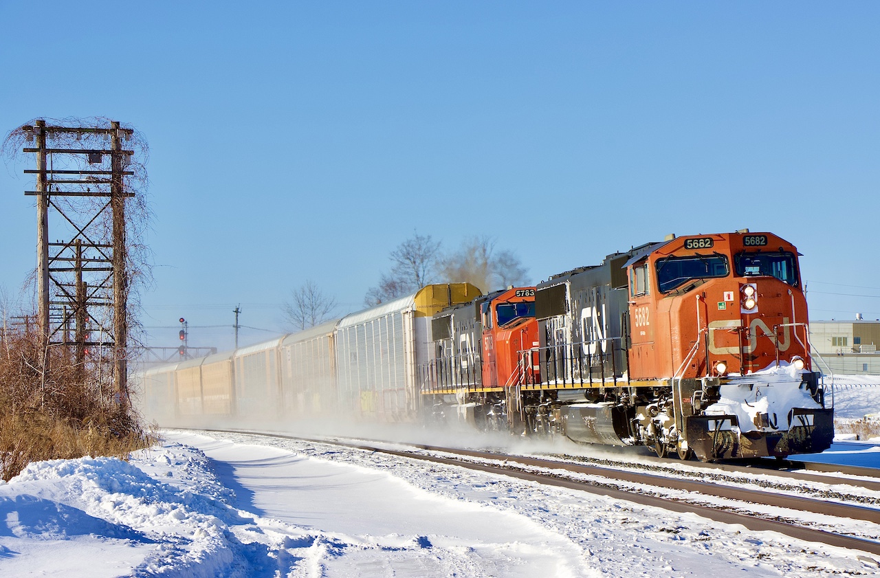 The SD70/75I was the first units I saw arrive brand new on CN’s roster. Seeing them being rebuilt now certainly makes me feel old. I remember seeing them in fresh paint, and now those that have yet to be rebuilt sport paint suffering from many years of service. Hard to believe I would be chasing these units in their original paint these days as they await their turn for a rebuild and AC conversion. After catching the train at Bowmanville my son and I wanted a decent side shot so we  headed for Coubourg to catch the pair kicking up snow on a -30 windchill day passing the VIA station. It appears 5682 has received a replacement snow plow possibly from a SD40 as the old white stripes are showing through the grime.