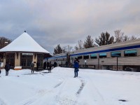 January 2026 at Parry Sound, Ontario. A portion of VIA Rail’s Canadian (Train 1, Toronto–Vancouver) stands during a scheduled fresh-air break, with the locomotives (VIA 6448 and 6457) just out of frame to the left. From this angle, the baggage car (8606) and first economy coach (8105) are visible as passengers detrain for their first opportunity to stretch their legs roughly five hours into the journey, having departed Toronto at 10:00 a.m. With no onboard Wi-Fi and limited cellular coverage along much of the route, the stop offers a brief chance to check phones, grab some fresh air, or — in the photographer’s case — dash out to document the train itself.

Photographic options here are limited by nearby residences, fencing, and the steep terrain, but the moment is anchored by the historic Canadian Pacific Railway station in the background. Built in 1907, the castle-like CP station ceased regular passenger service in 1990 and today houses the Festival of the Sound offices. VIA Rail continues to use this location, known operationally as Parry Sound South, for westbound service, while eastbound trains call at the former CN station elsewhere in town — a reminder of Parry Sound’s layered railway history.