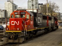 A pair of CN SD60s await their next job in the small CN New Westminster Yard. The locomotives look small compared to the modern high rise buildings in the background. 