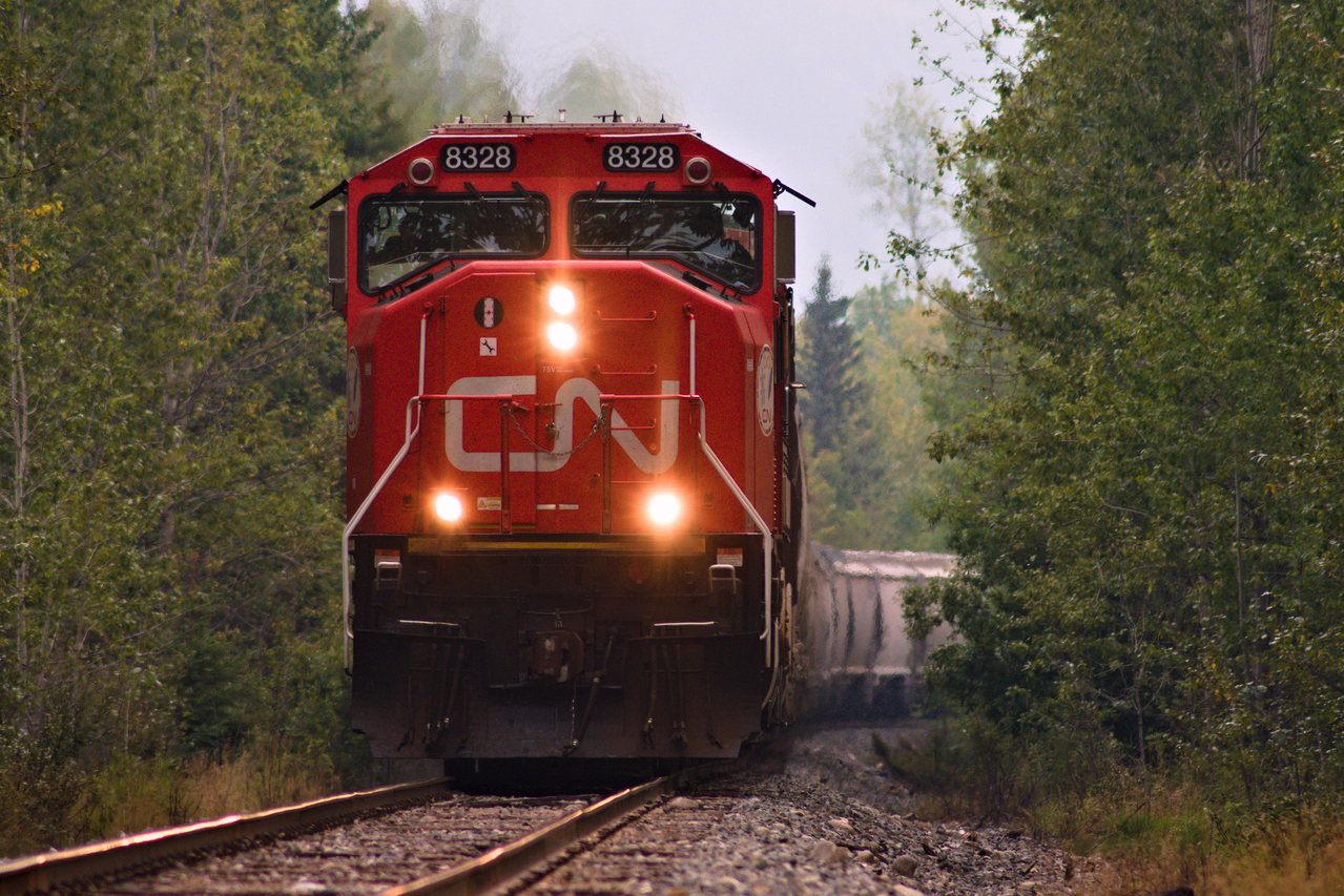 CN 8328 leads a heavy sand train north to Fort St. John. This was the longest train I have ever seen, at 830 axels, and also two mid remotes! The train was broken up into two parts, one half was sand, and the other half being LPG. Note the heavy smoke in the air.
