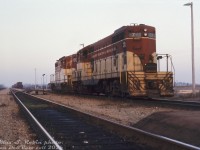 TH&B GP7 77 and GP9 402 sit near the PC-TH&B yard office/station building at Welland Yard, a few tracks over from the PC Canada Division mainline on the left. (the old Canada Southern/CASO line through southern Ontario). This appears to be an evening shot, perhaps power for a TH&B job waiting to lift its train and head back to Hamilton (one of the resident TH&B experts may have more insight).
<br><br>
<i>Max S. Robin photo, Dan Dell'Unto collection slide.</i>