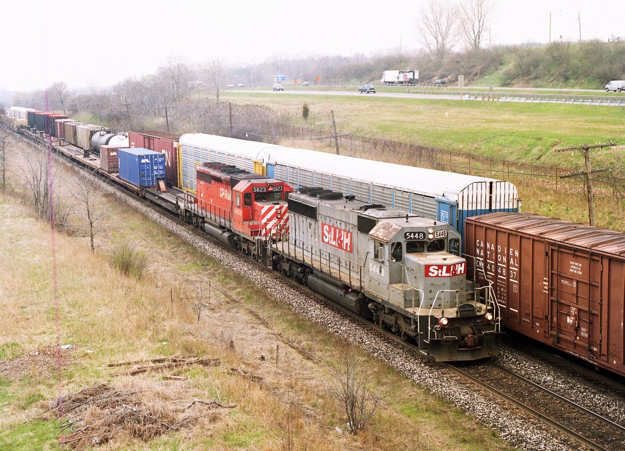 STLH 5448 leads CP 5623 eastward as seen from the Lemonville Rd bridge in Aldershot. The 5448 was readily identified with its large 'STLH' patches; the only one of its kind.
There was a trio of locomotives around back at that time which were referred to as "The Ugly Sisters", namely 5447, 5448 and 5449. The 5447 was the most pitiful, with "CP" applied with what looked like a roller brush on a rust coloured body. The 5448 was most distinctive, and I enjoyed seeing this one as a leader.