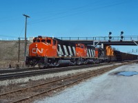 GP40-2LWs 9620 and 9411 along with GP9 4527 lead train 463, the "pulp train" (MacMillan Yard-Fort Erie), past Aldershot Yard and the Cold Storage building on a nice day in the spring of 1977. Note the dimensional load behind the power, where the crew can keep an eye on it.