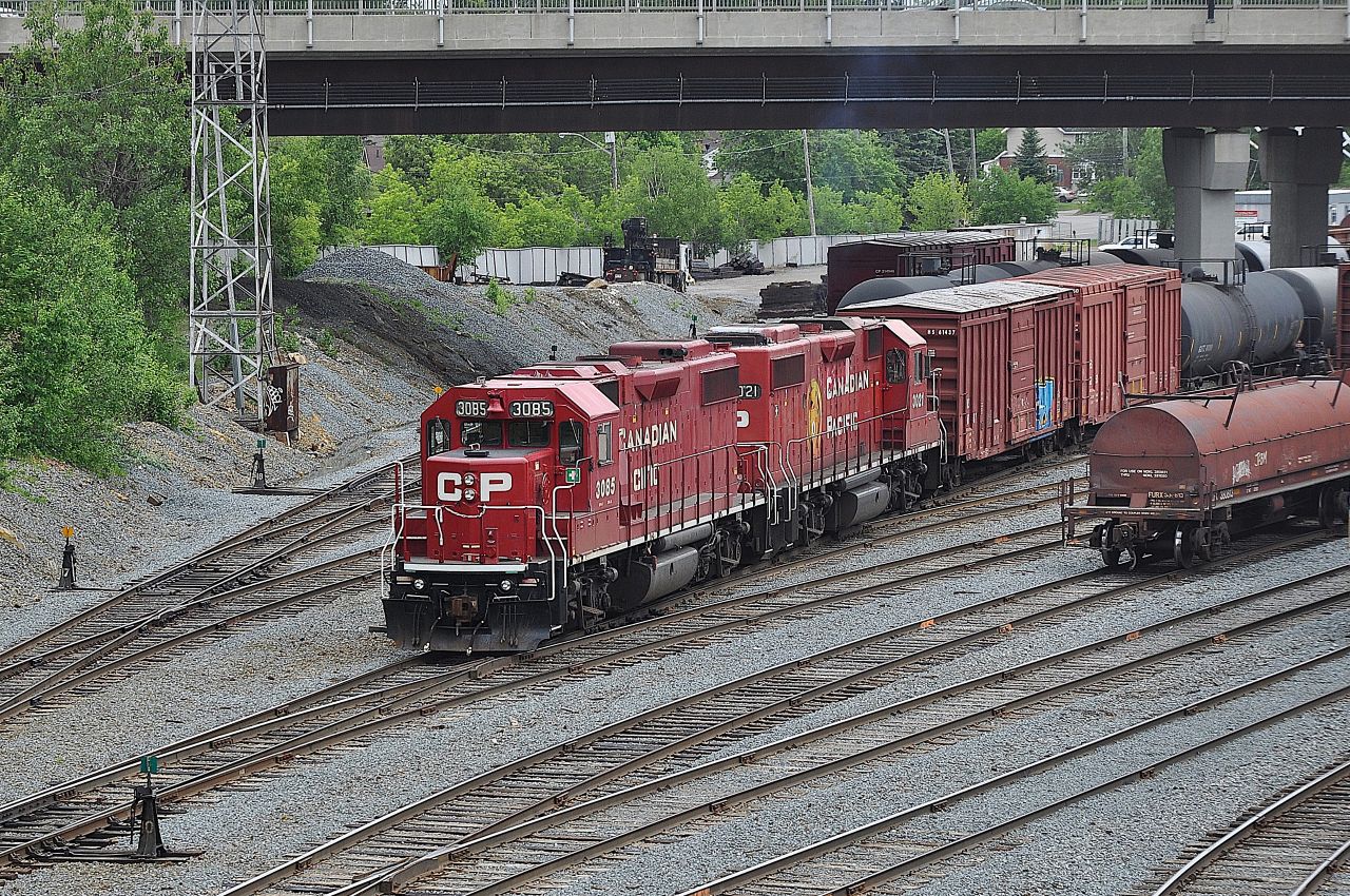 A pair of CP GP38-2s, 3085 and 3021, are bashing cars around in CP's small Sudbury, Ontario yard under the Paris Street bridge.