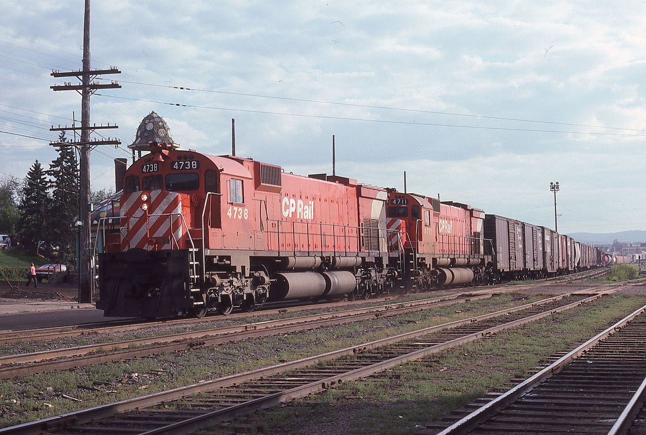 A westbound CP freight lead by a pair of MLW M-636s, 4738 and 4711, roll past the old Canadian National station in Thunder Bay Ontario on July 27. 1977.