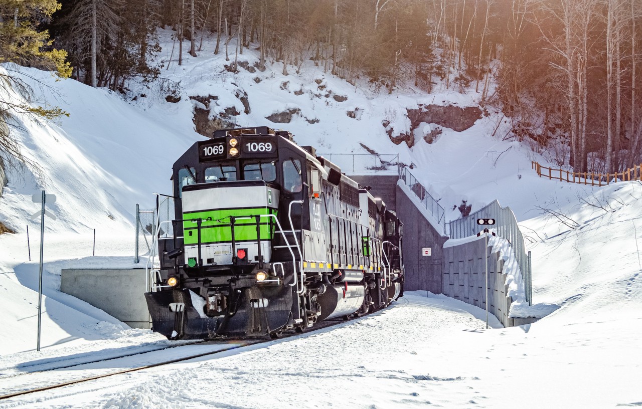 Just over a month ago, in January 2026, the Société du Chemin de Fer de la Gaspésie resumed freight service on its railway between New Richmond and the Port-Daniel cement plant. Since 2013 when the railway shut down, the tracks were completely overhauled, many bridges and crossing signals were replaced, new retaining walls were built, the Port-Daniel tunnel was enlarged and the track even was relocated slightly at some places, to fight coastal erosion. Here we see the westbound trip as it just got out of the tunnel, which features some new concrete portals. For the time being, trains only run up to 15 miles per hour, stopping at a few unactivated railway crossings and making the round trip between New Richmond and Port-Daniel over the course of 2 days.